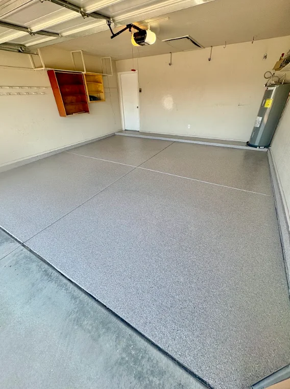 Professional garage floor installation workspace with diamond grinding equipment and sealed concrete floor ready for coating application.