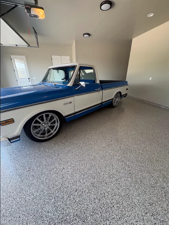 Freshly coated garage floor in a Gilbert, AZ home showing a smooth, glossy surface with a decorative chip finish. The desert-facing garage interior is clean and dust-free with the coating fully cured.